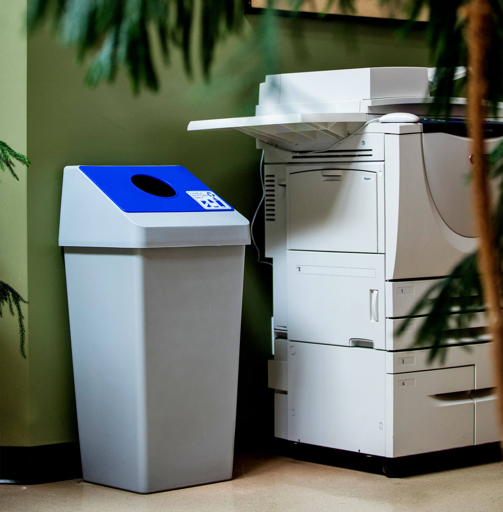 plastic cans and bottles recycling container with a sloped lid sitting beside a printer in a university office