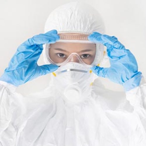 Person wearing a white personal protective suit, blue gloves, and safety goggles.
