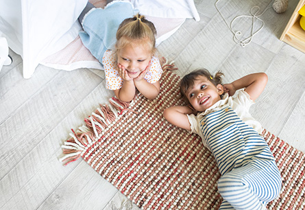 Two children lounging on the floor smiling