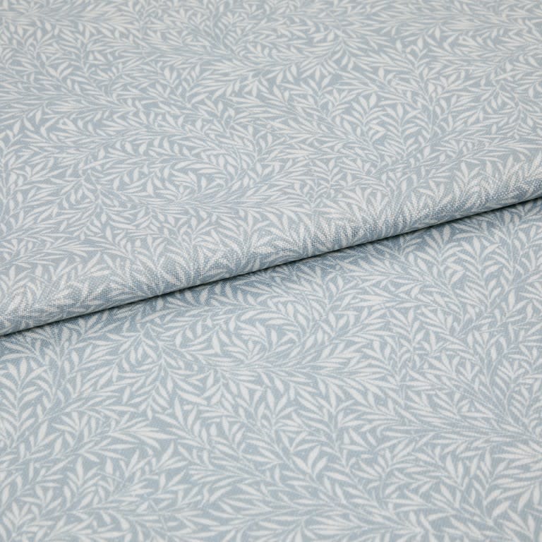 Light-blue printed fabric with a white leaf motif folded once and overlapping; close-up of a soft woven textile surface under even, neutral lighting.