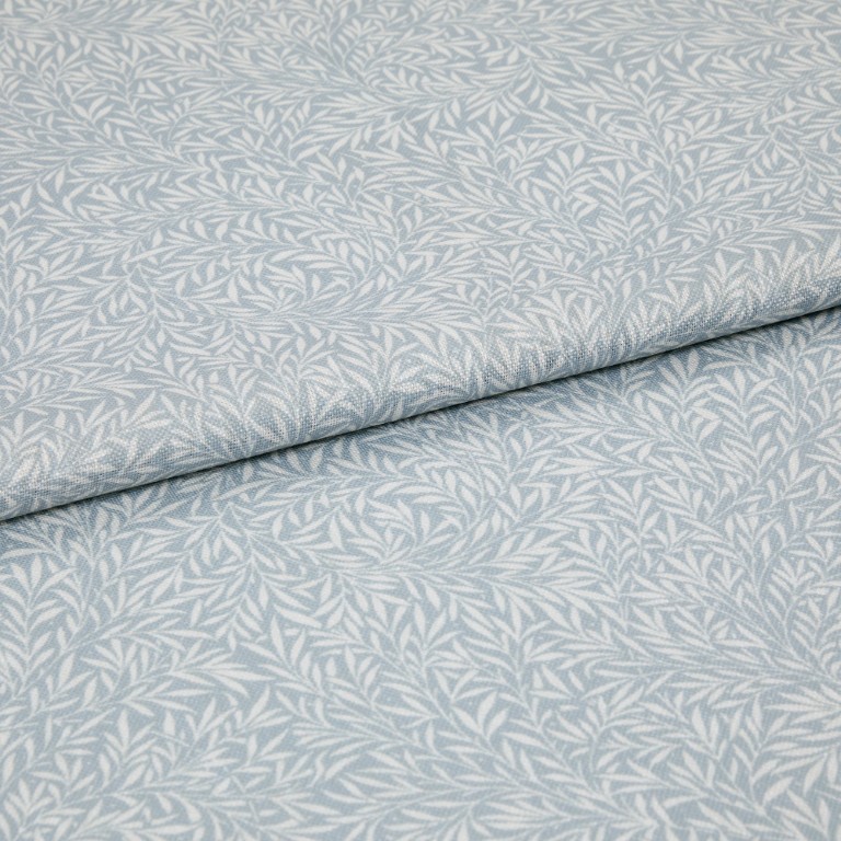 Light-blue printed fabric with a white leaf motif folded once and overlapping; close-up of a soft woven textile surface under even, neutral lighting.