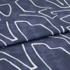 Navy-blue fabric with white abstract linear print, folded once; fabric rests flat, studio-lit close-up revealing woven texture and a visible fold/seam.