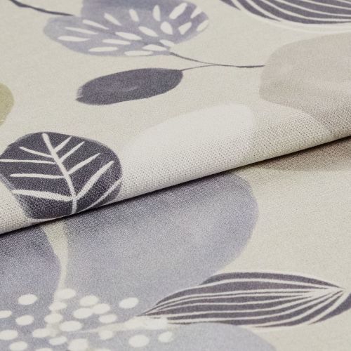 A folded beige curtain fabric with stylized gray and lavender leaf prints (textured knit), overlapping to show the hem and pile, photographed close-up on a neutral surface under soft lighting.