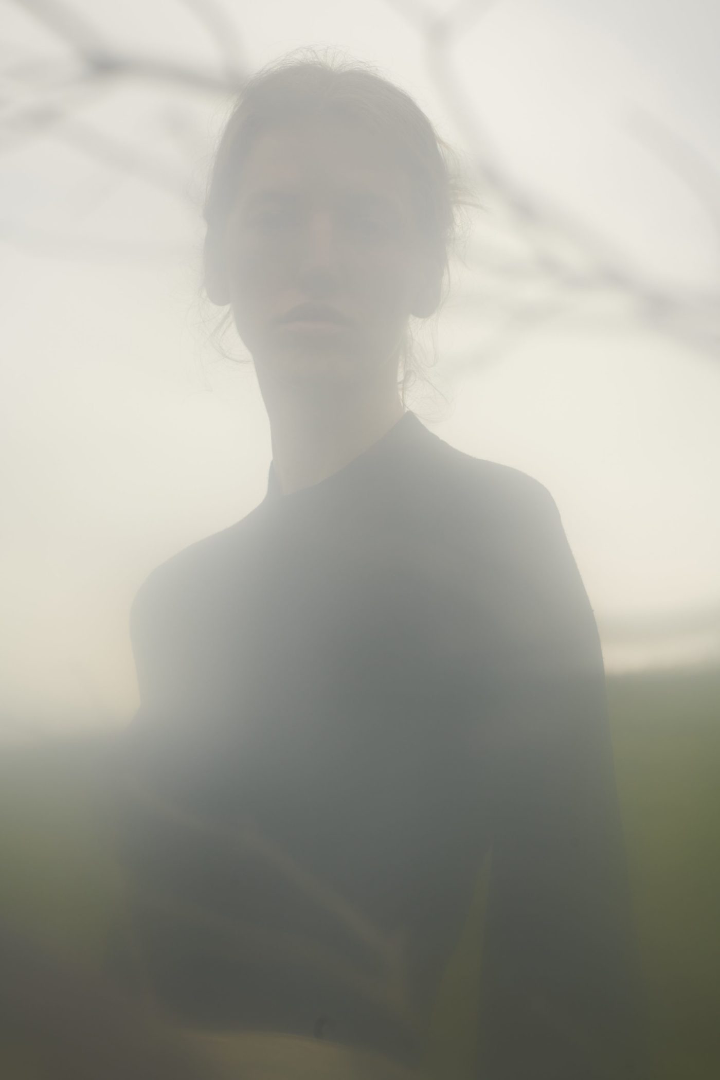 a woman is standing in a foggy field.