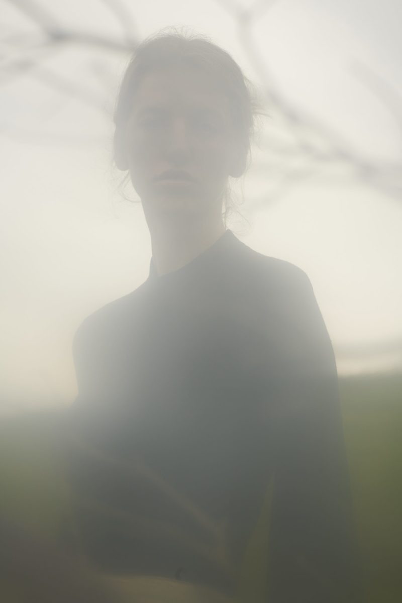 a woman is standing in a foggy field.
