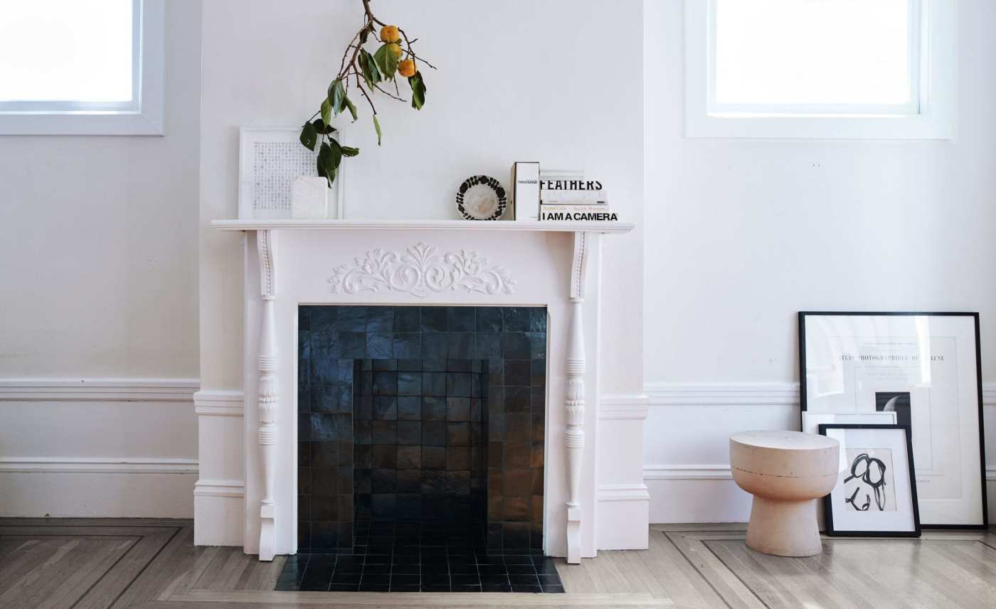 a green tile fireplace in a room with white walls.