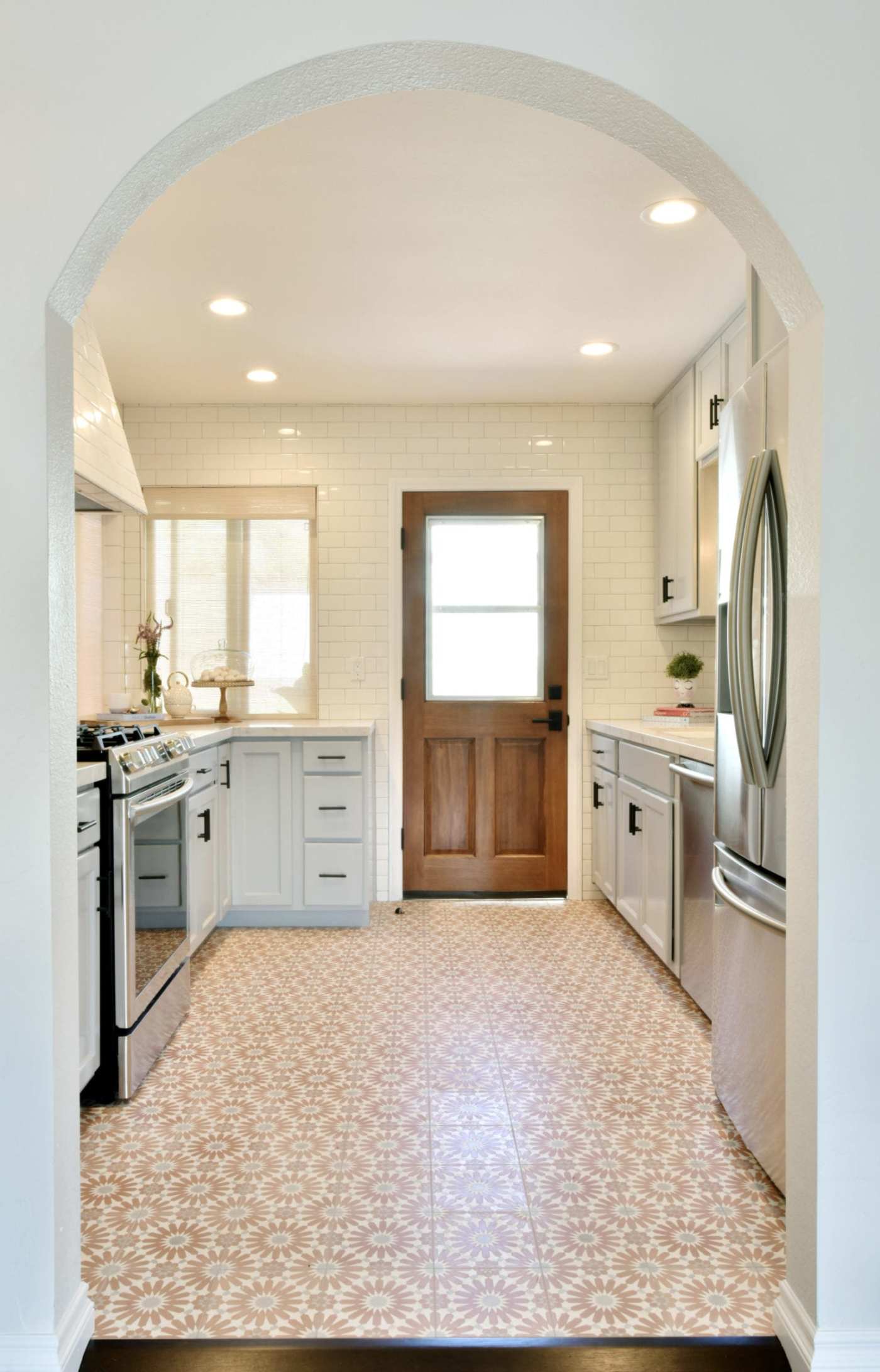 a kitchen with an arched doorway and white cabinets.