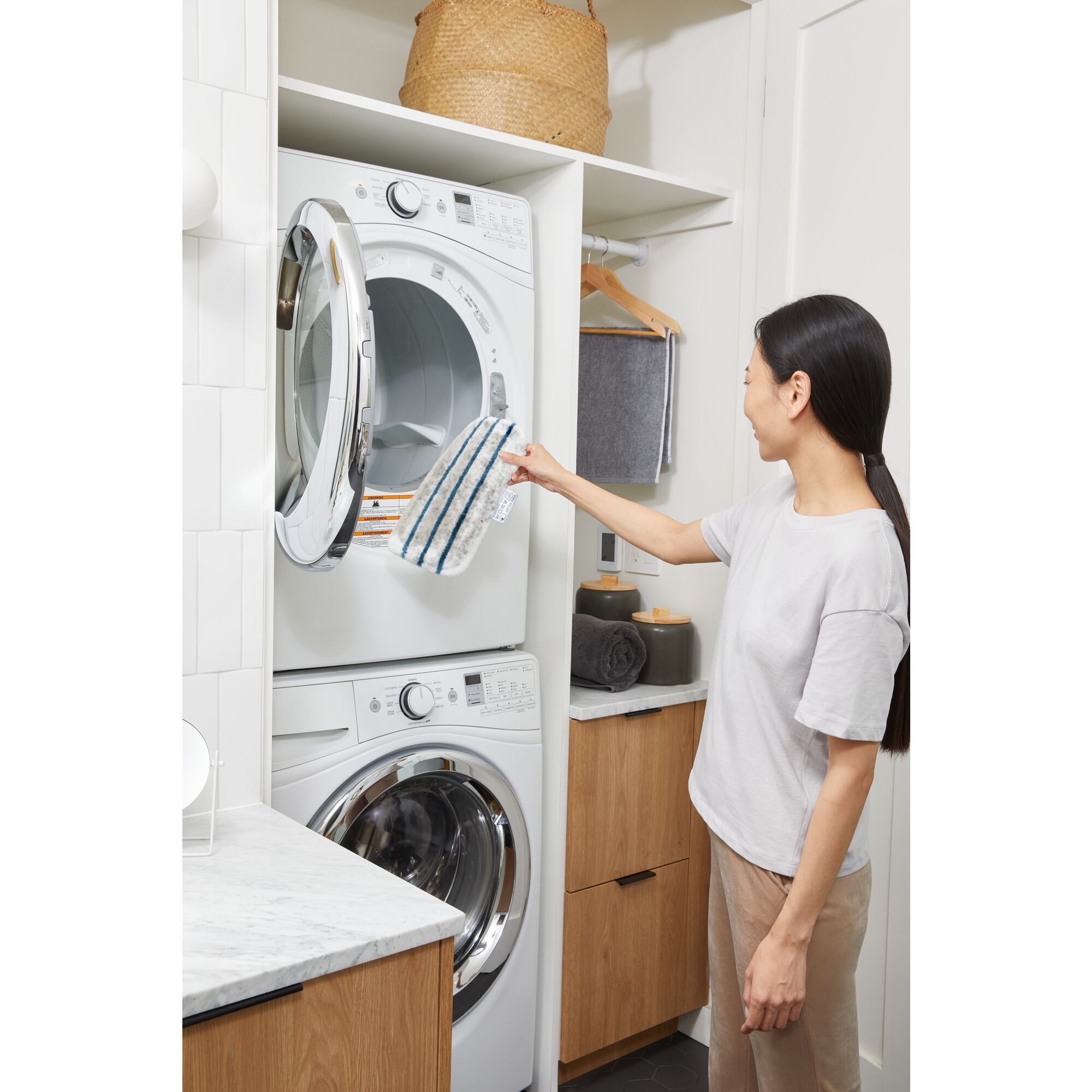 Woman tossing the removable steam mop cleaning pad into a washing machine