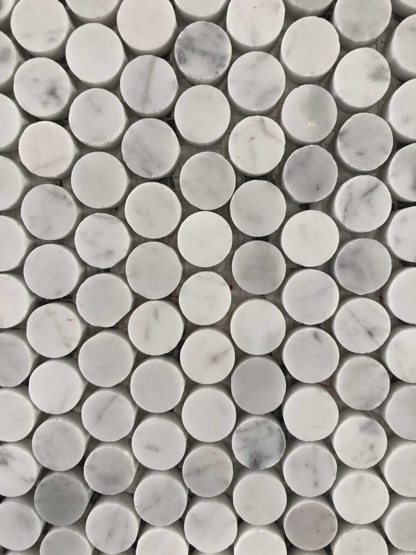 a close up image of a sheet of penny shaped white marble tiles.