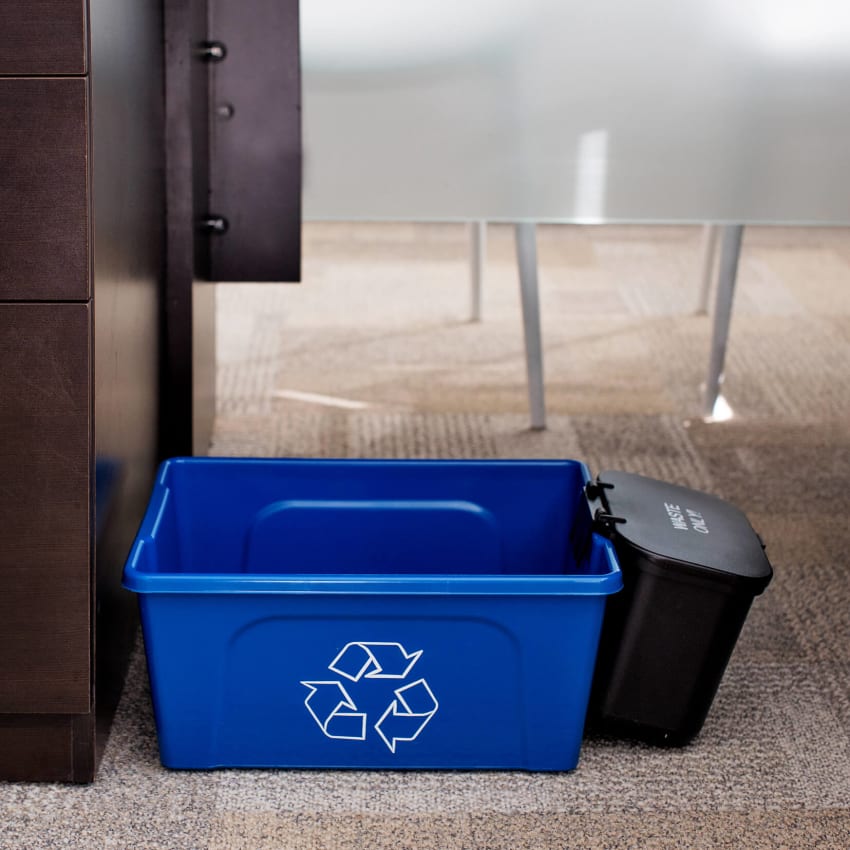 blue deskside recycling container with black hanging waste basket with lid under an office desk