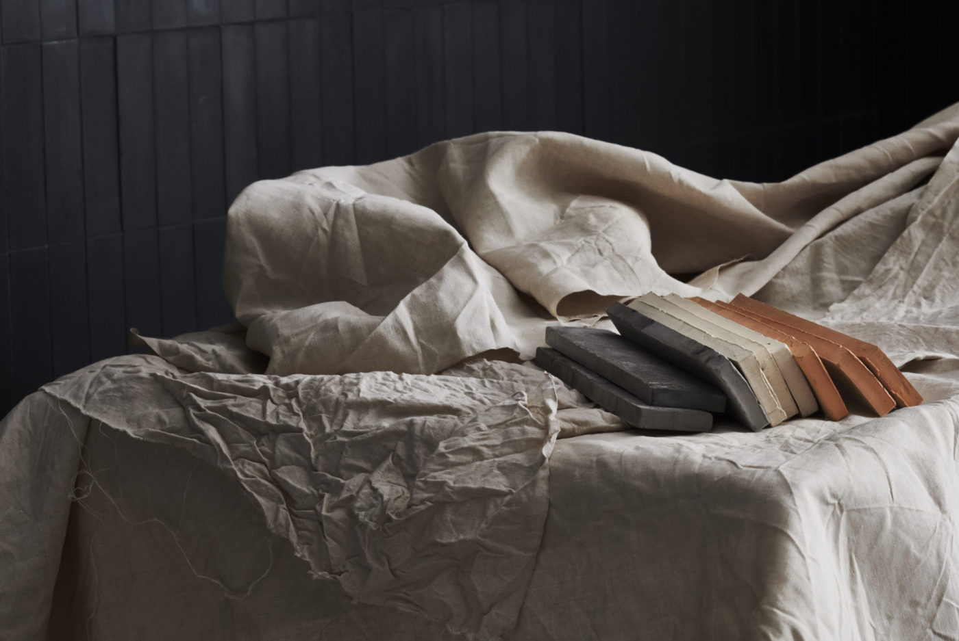 a stack of grey, white, and red rectangle tiles on a white bedsheet.