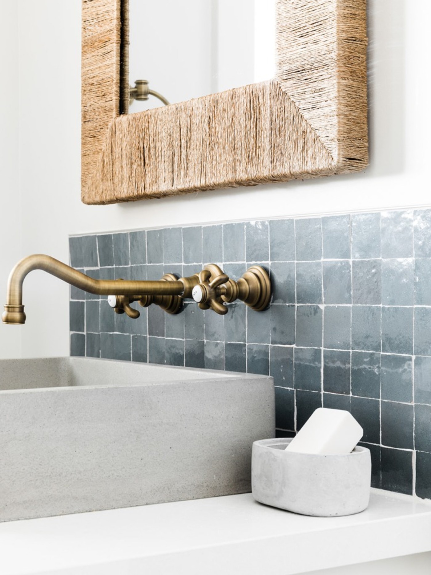 a bathroom sink with blue tile backsplash and a mirror.