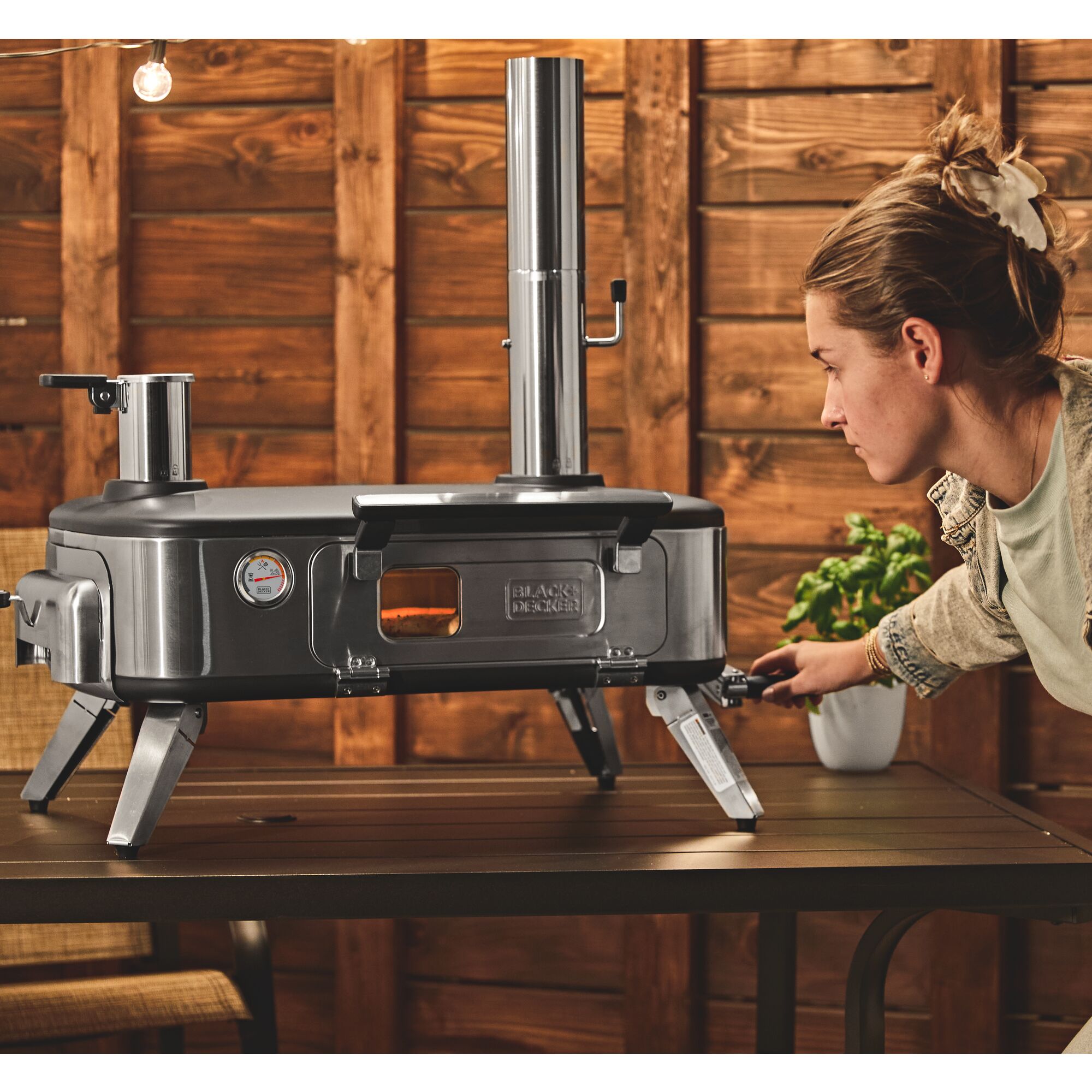 Talent using the rotating handle feature on the BLACK+DECKER vera™ 12 in. pizza oven