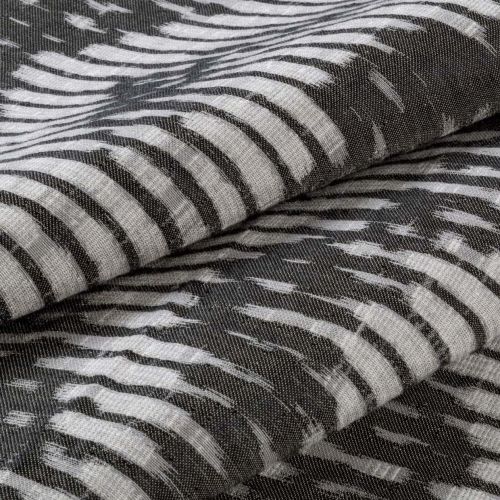 Folded woven fabric with irregular white brushstroke stripes on a dark background â€” stacked in overlapping layers â€” close-up of textured, soft textile under neutral, diffuse lighting.