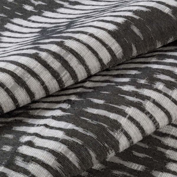 Folded woven fabric with irregular white brushstroke stripes on a dark background — stacked in overlapping layers — close-up of textured, soft textile under neutral, diffuse lighting.