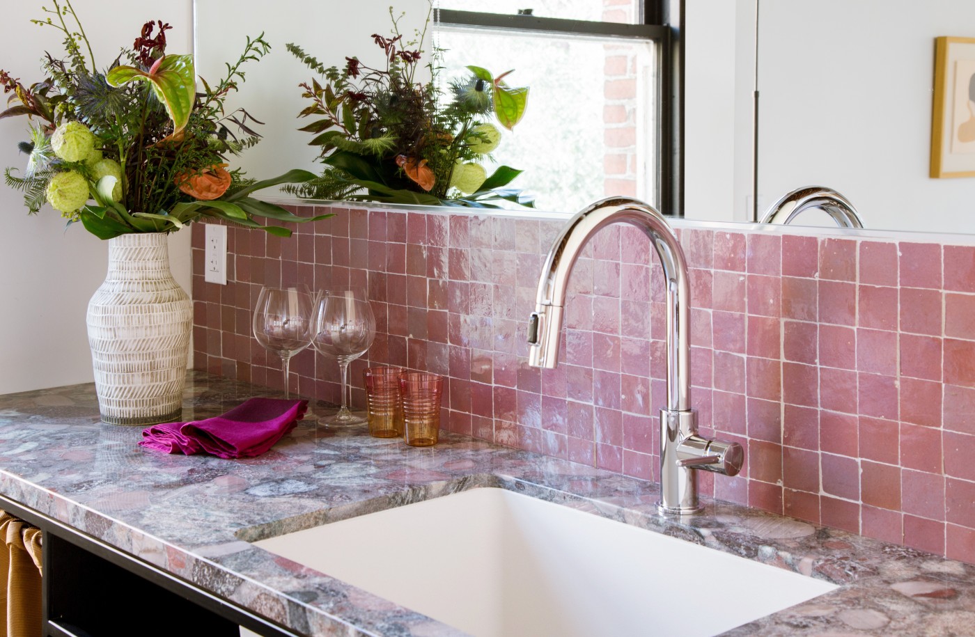 a sink with a pink tiled backsplash.