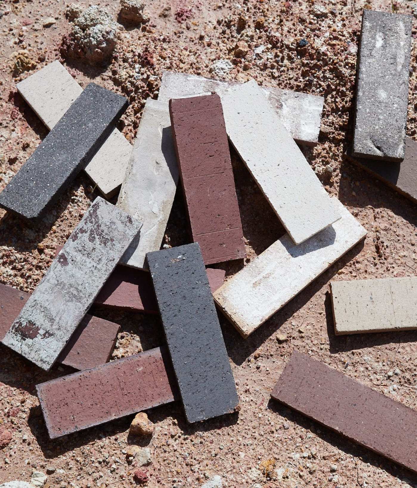 various colored brick tiles scattered across a dirt surface.