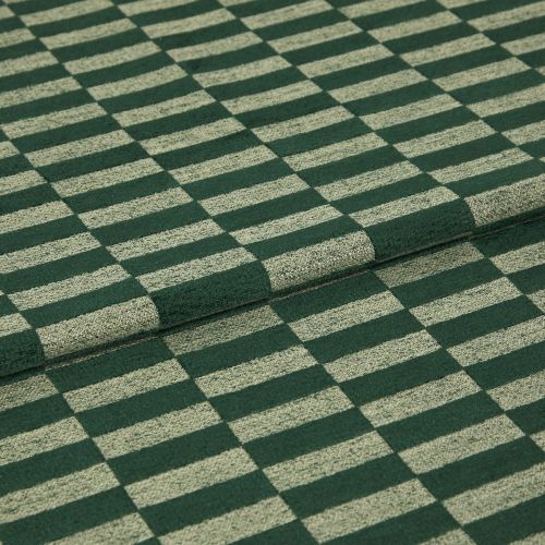 Green-and-beige rectangular checkered fabric folded in two, showing textured loops; laid flat in a close-up studio shot, highlighting the woven pattern and soft upholstery or rug material under neutral lighting.