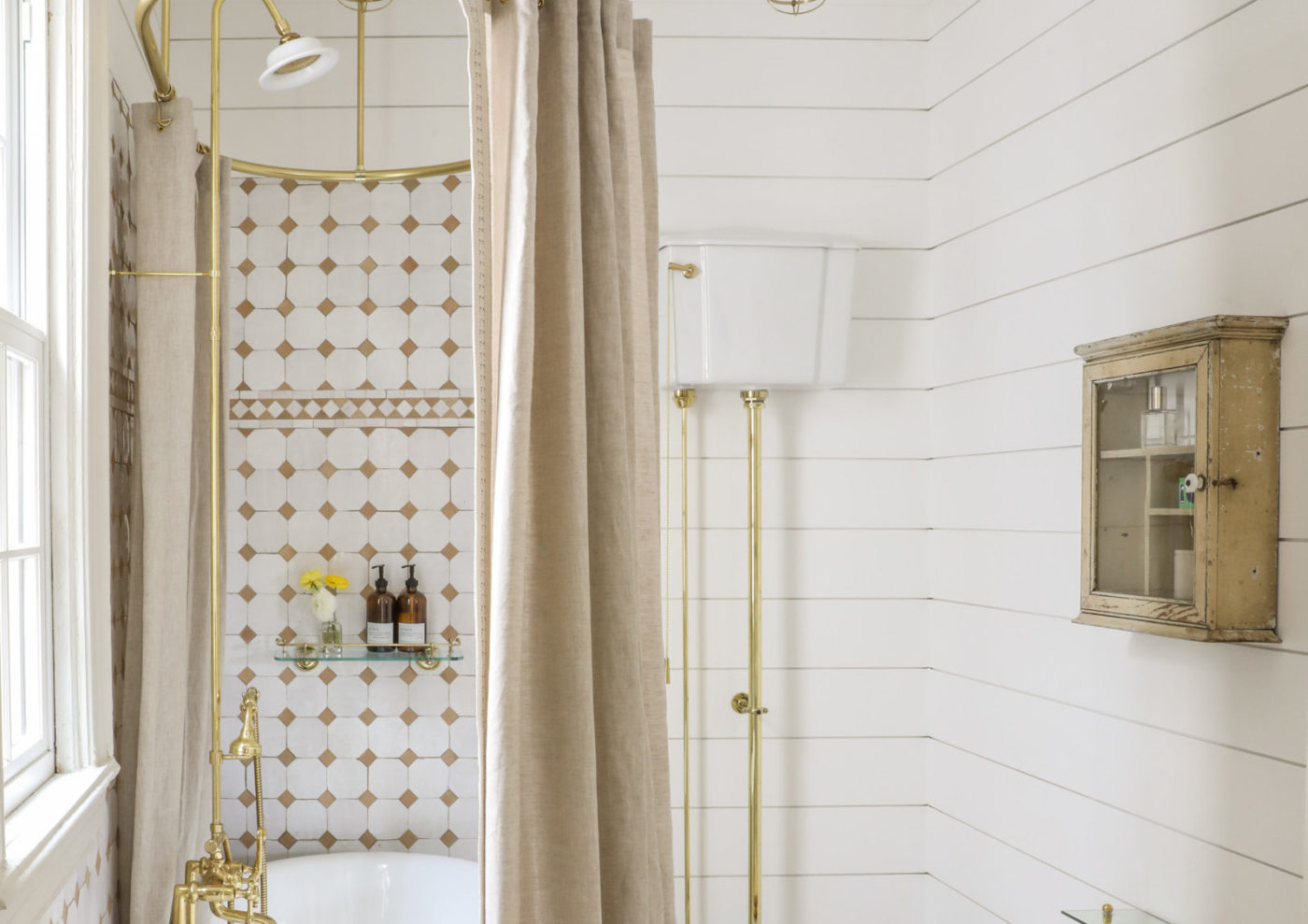 a white and gold bathroom with a tub and shower.