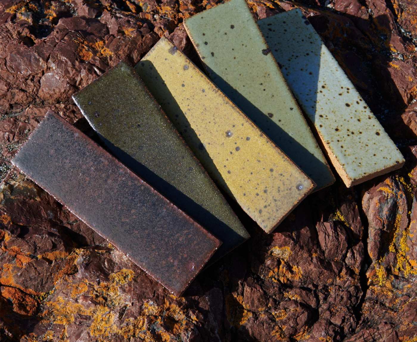 five different colored tiles laying on top of a rock.