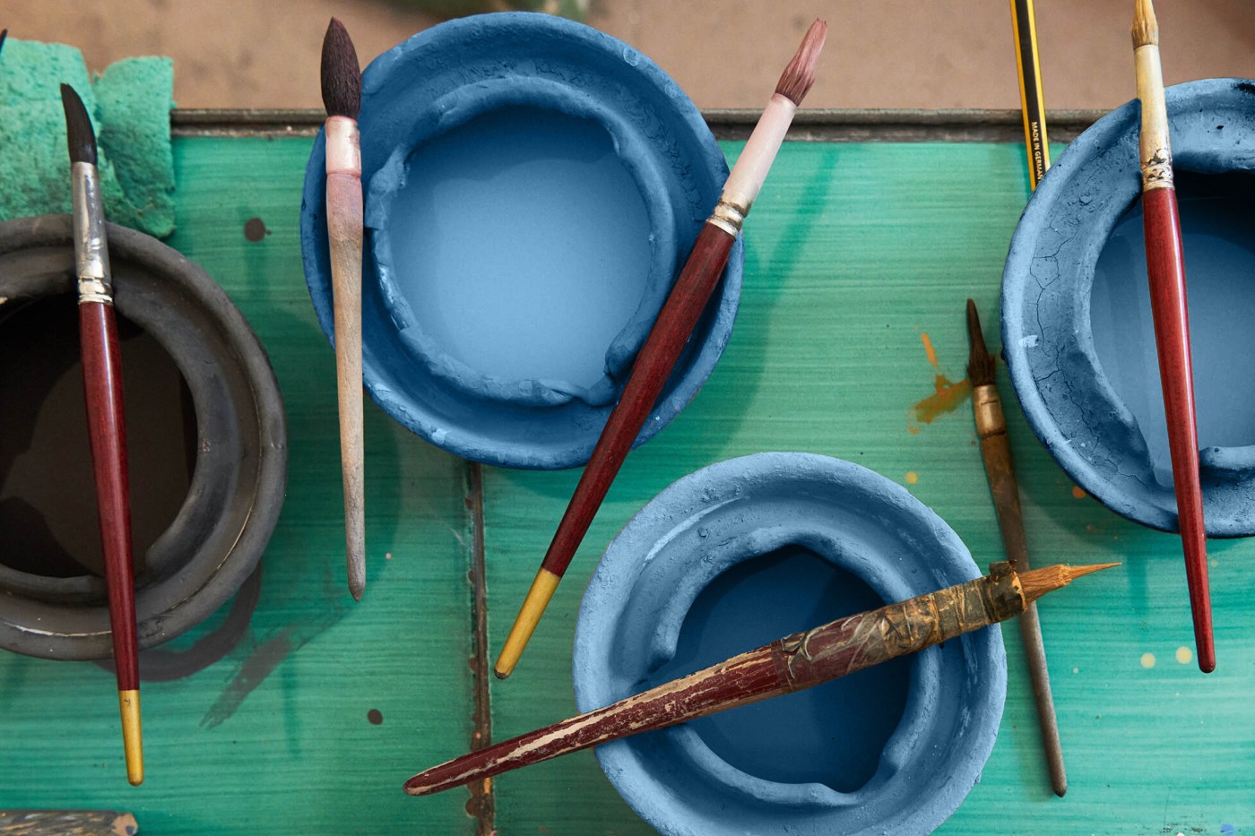 a group of paint brushes and bowls on a table.