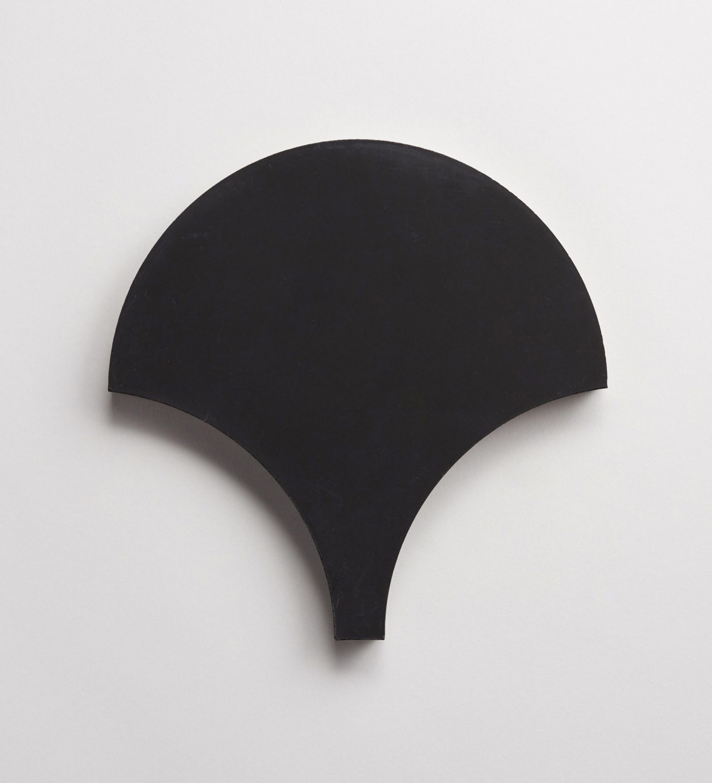 a black scallop-shaped tile on a white background.