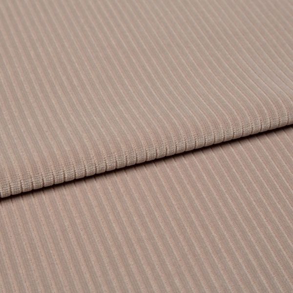 Ribbed beige corduroy fabric, folded into two layered panels showing parallel ridges, photographed close-up on a neutral surface with soft, even studio lighting.