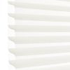 White horizontal pleated cellular blind with scalloped edges, fully lowered and closed, filtering bright daylight; close-up view showing soft shadowed ridges against a pale background.