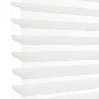 White horizontal pleated cellular blind with scalloped edges, fully lowered and closed, filtering bright daylight; close-up view showing soft shadowed ridges against a pale background.