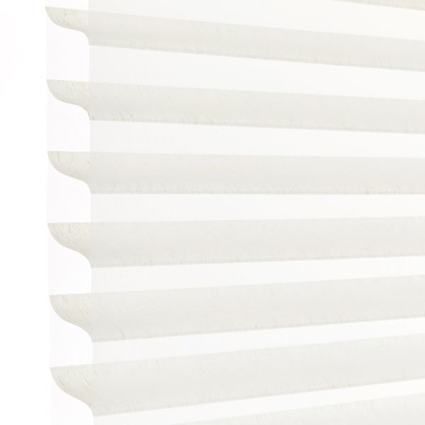 White horizontal pleated cellular blind with scalloped edges, fully lowered and closed, filtering bright daylight; close-up view showing soft shadowed ridges against a pale background.