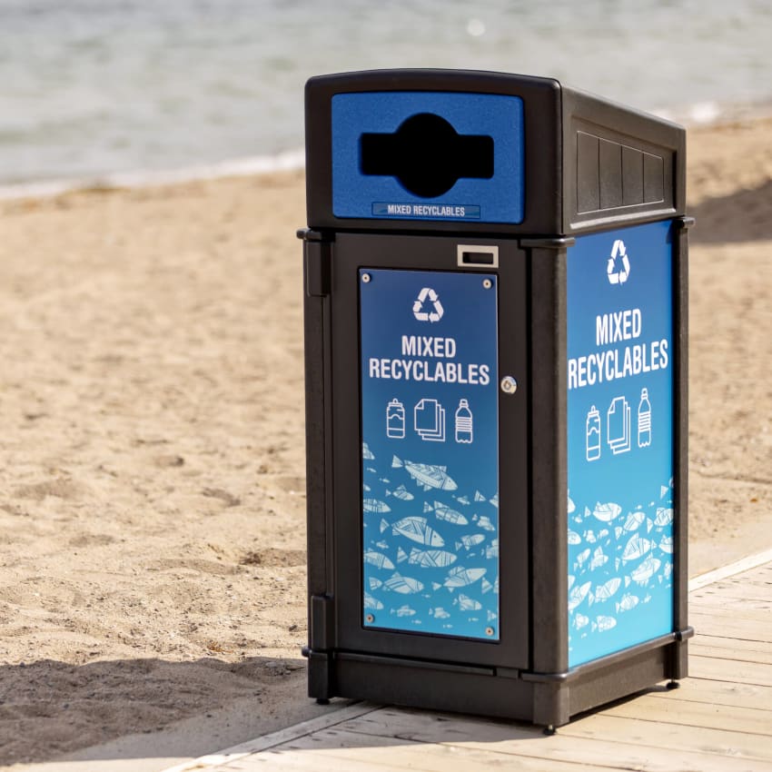 outdoor durable black recycled plastic mixed recyclables bin with restrictive opening on a boardwalk along with waterfront including fun bright signage