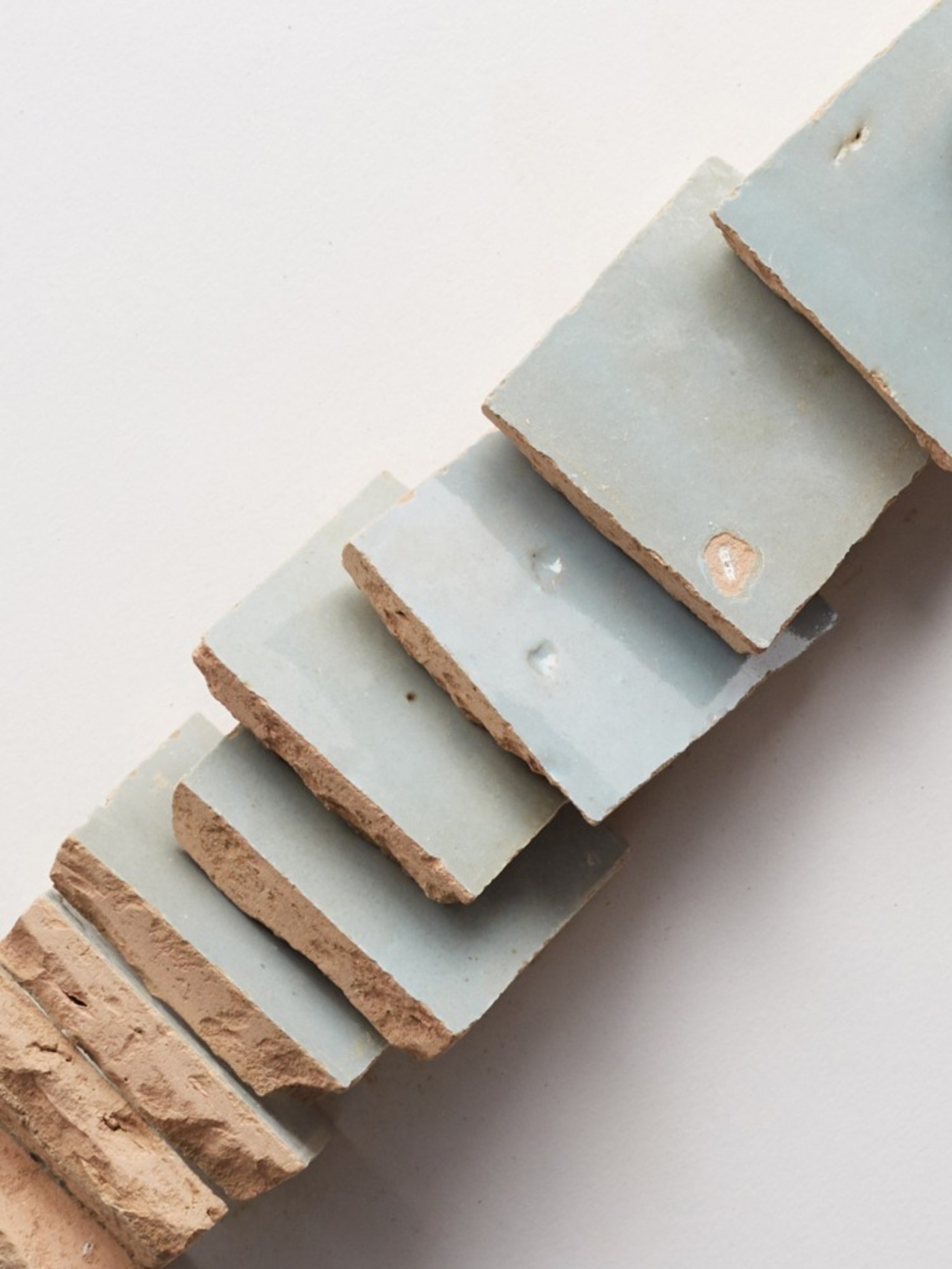 a stack of blue ceramic tiles on a white surface.