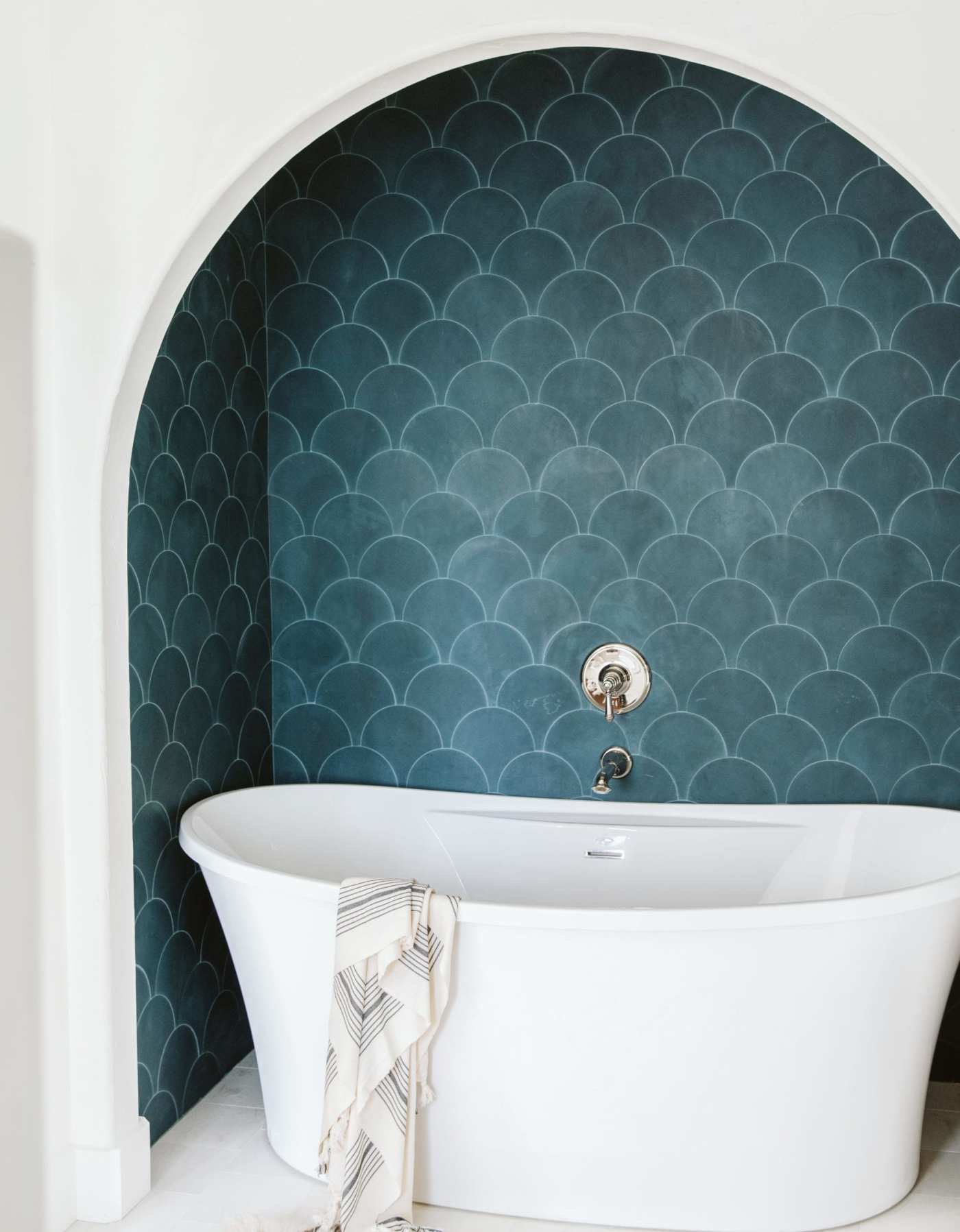 a bathtub in front of a blue tiled wall.