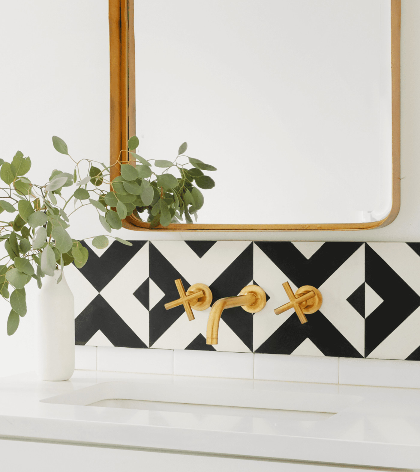 a black and white bathroom sink backsplash below a mirror.