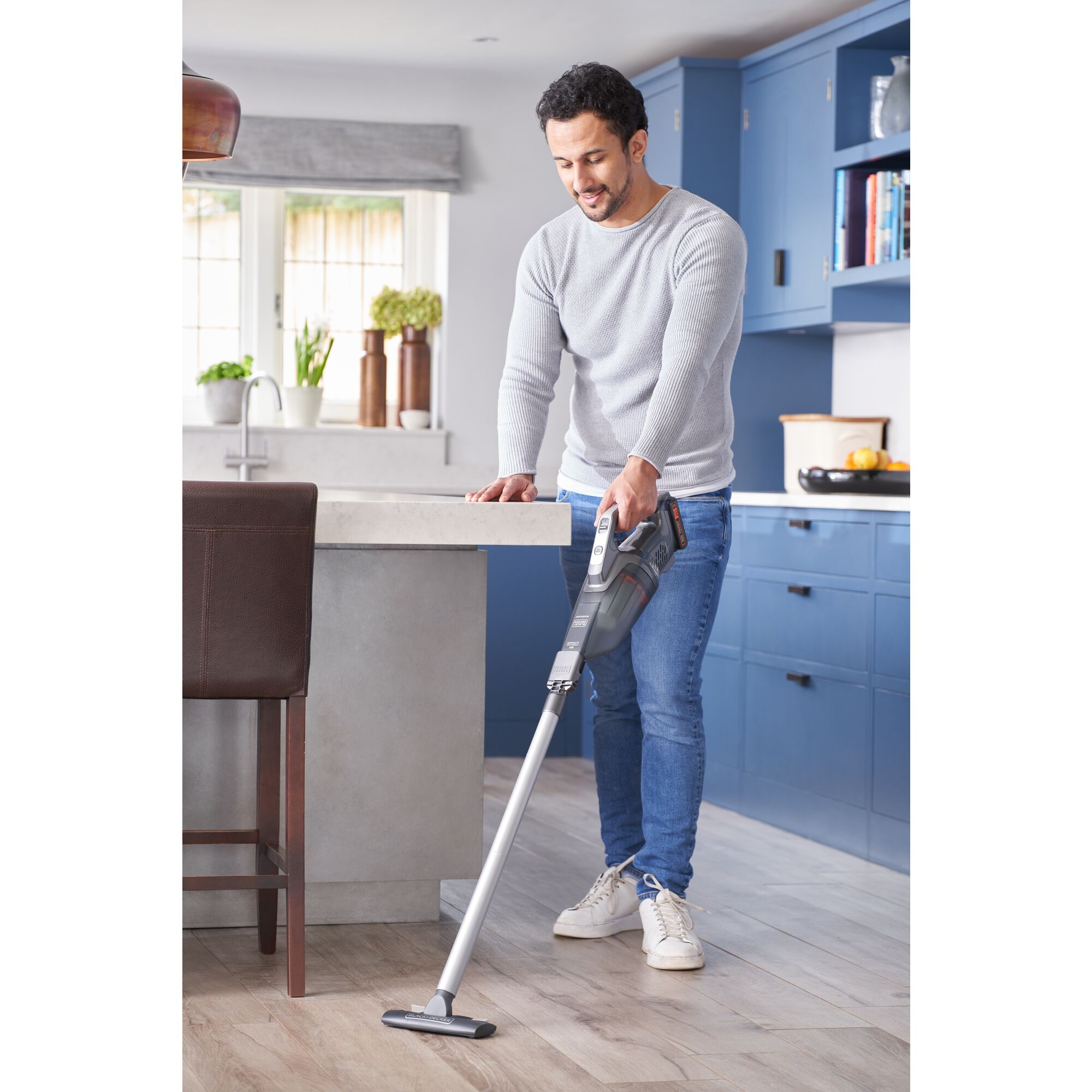 Person using 20 volt MAX Powerconnect handheld vacuum extension to clean up hard kitchen floor surface