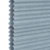 A light-blue honeycomb (cellular) blind, hexagonal cells visible along the left edge; closed into uniform horizontal pleats, blocking view and filtering light, shown in a close-up with soft, neutral lighting.