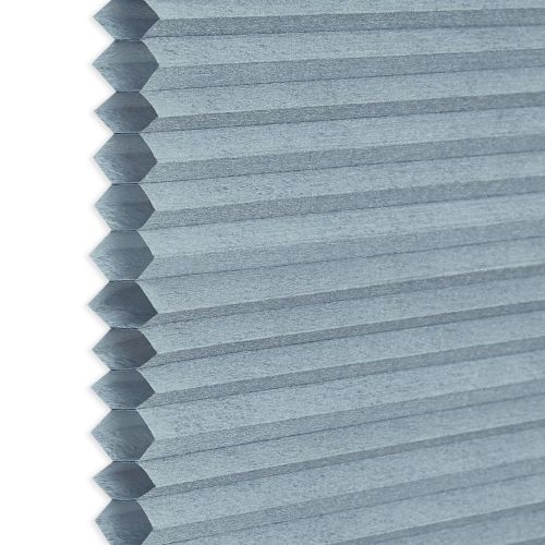 A light-blue honeycomb (cellular) blind, hexagonal cells visible along the left edge; closed into uniform horizontal pleats, blocking view and filtering light, shown in a close-up with soft, neutral lighting.
