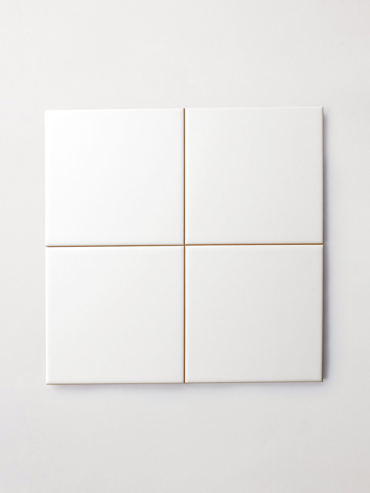 four white square tiles on a white surface.