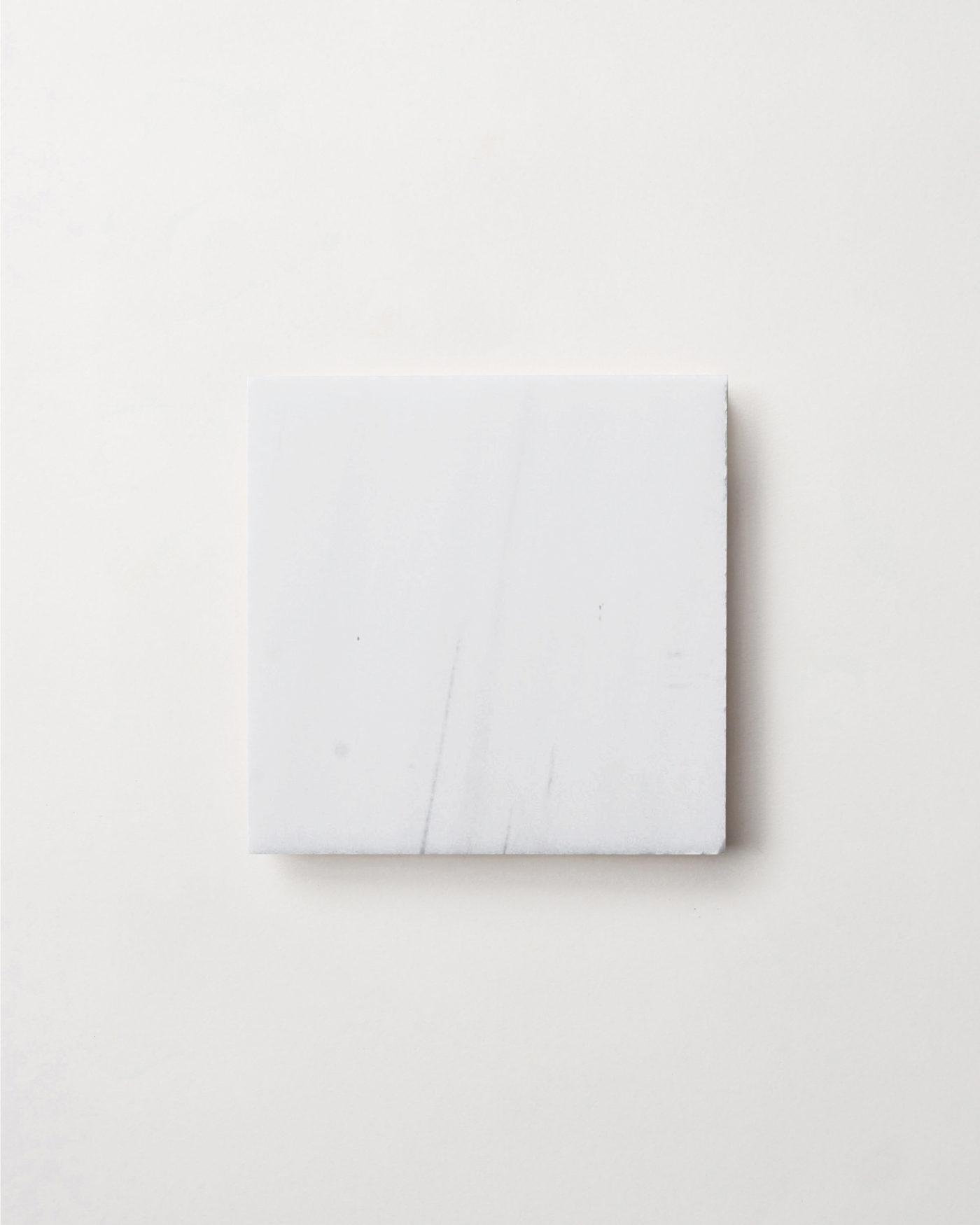 a white square tile on a white surface.