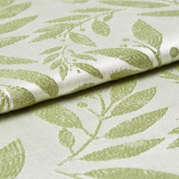 Folded jacquard fabric with raised pale-green leaf pattern on a cream background; fabric overlaps and rests, shown in a close-up view with soft directional lighting revealing its texture.