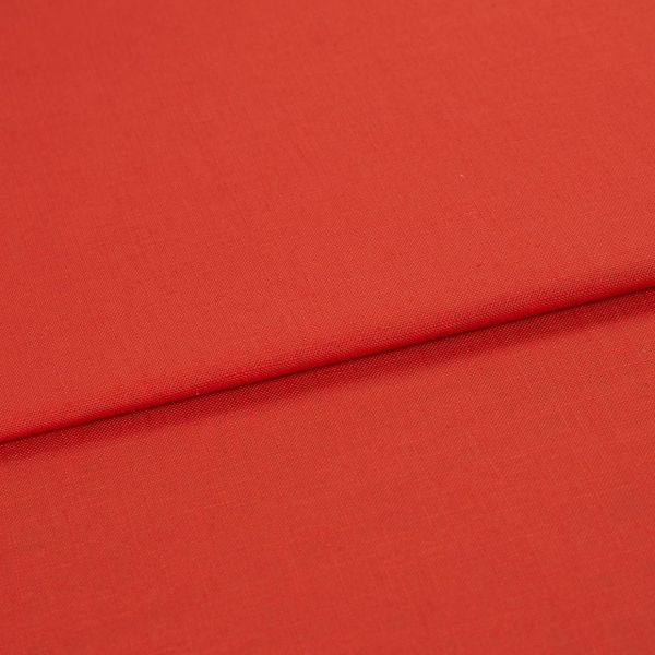 Red woven fabric panel with visible fine texture, folded across the frame forming a horizontal overlap; lying flat under soft, even studio lighting with no other objects or background details.