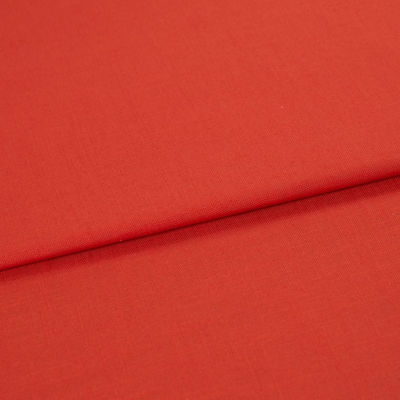 Red woven fabric panel with visible fine texture, folded across the frame forming a horizontal overlap; lying flat under soft, even studio lighting with no other objects or background details.