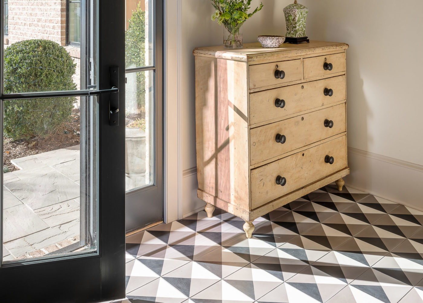 a black and white tiled floor in an entryway with an open door.