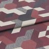 Woven jacquard fabric with burgundy, navy, gray and offâ€‘white 3D cube pattern; folded once with overlapping edge; close-up on a flat surface under soft, diffuse studio lighting.