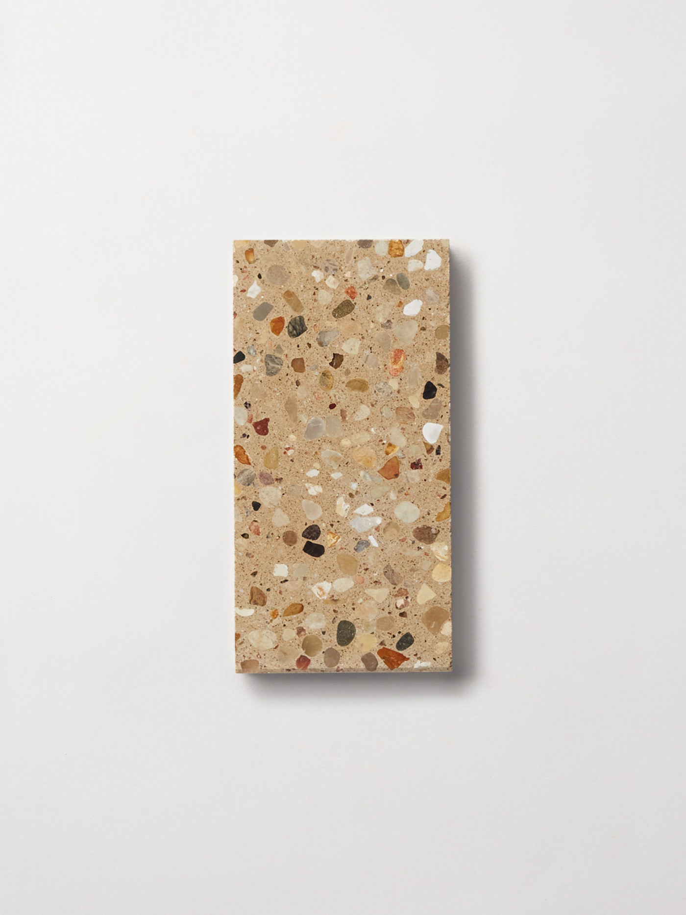 a beige rectangle tile with a terrazzo pattern on a white surface.
