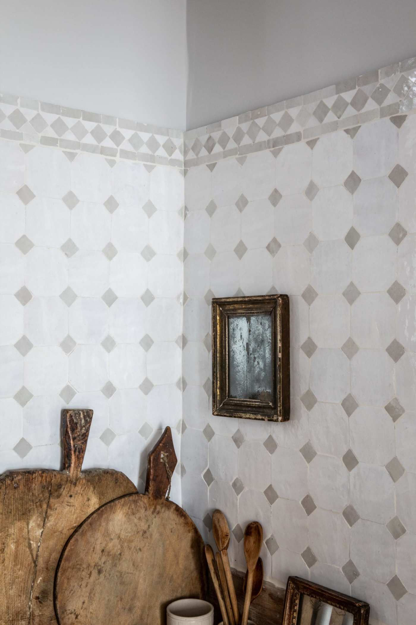 a kitchen counter corner with a white tiled wall and wooden utensils.