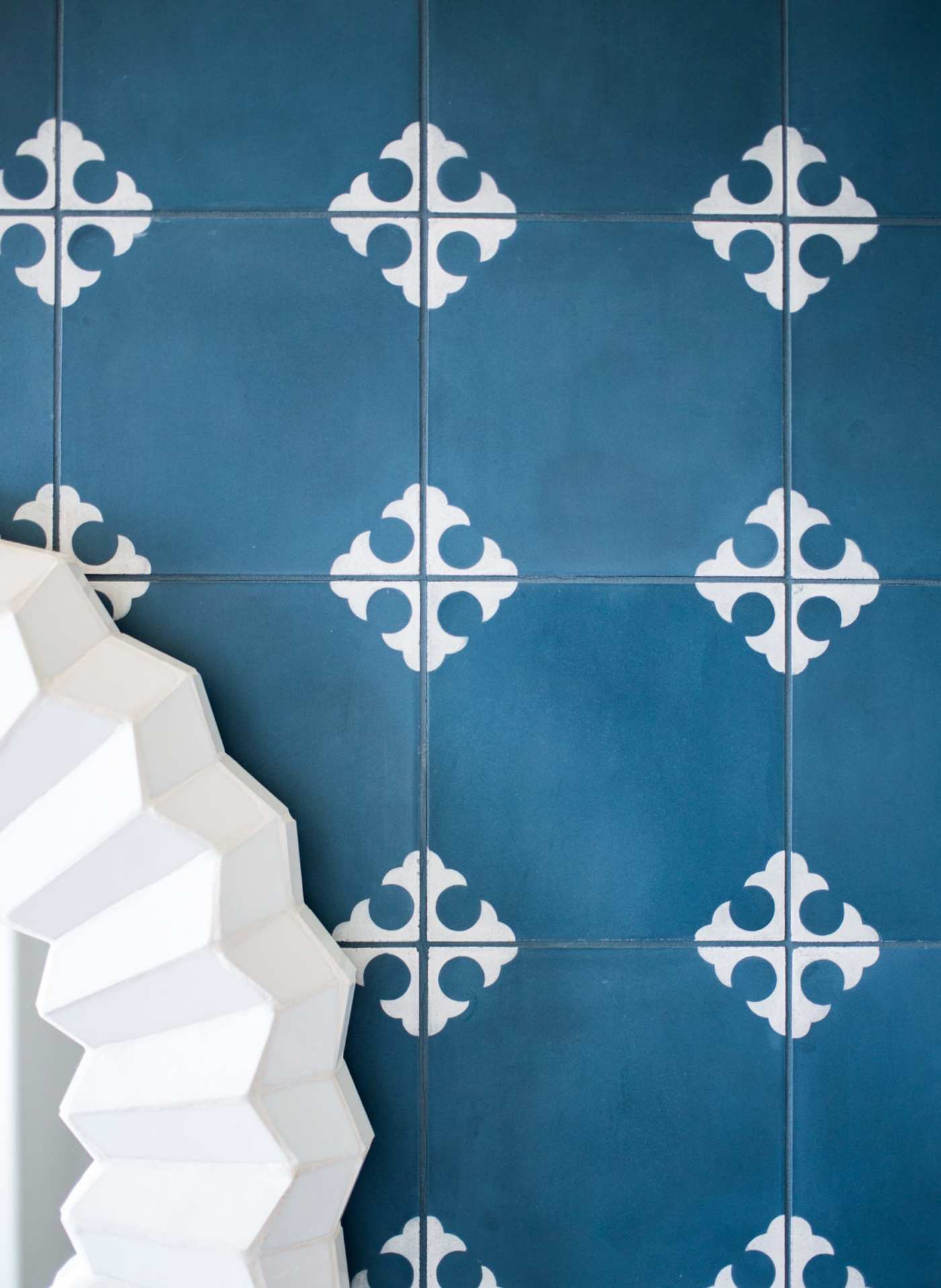 a blue and white tiled wall next to a mirror.