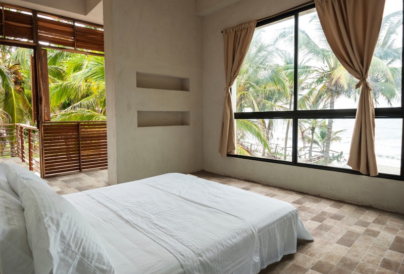 a white bed in a bedroom with a view of the ocean.