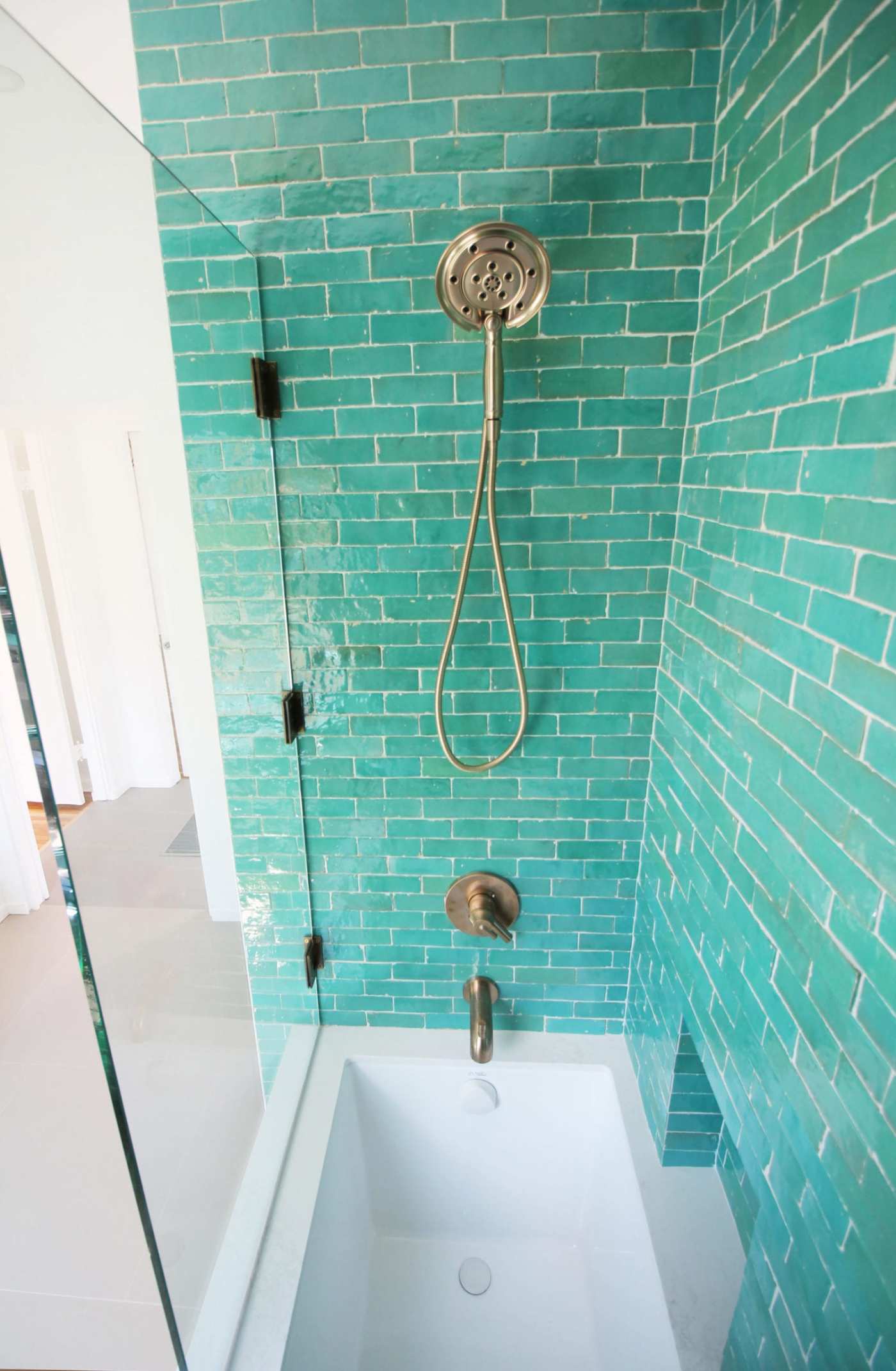 a bathroom with green tile shower.