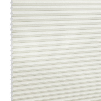 White cellular (honeycomb) blind, fully lowered and closed, its horizontal pleats visible; gently diffusing light in a neutral interior, shown in a close-up angled view.